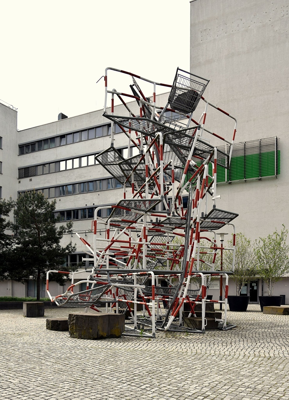 Foto einer meterhohen Skulptur aus ineinandergestapelten Polizeiabsperrgittern.