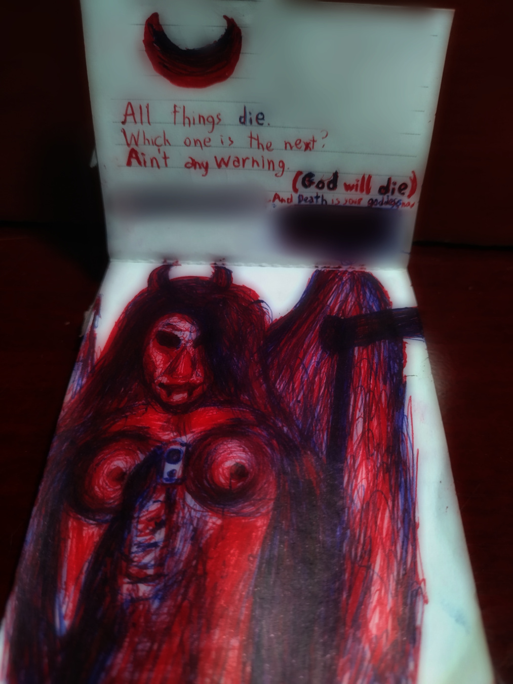A shot from a tilted angle showing two pages of a pocket notepad. The uppermost page has a hand drawing of a crescent moon pointing upward, followed by a text:

"All things die.
Which one is the next?
Ain't any warning.
(God will die)
And Death is your goddess now."

The bottom page features a handmade drawing of a feminine figure with hollow black eyes, devilish horns, long dark hair, sharp chin and nose, explicit breasts, vampire fangs and blood streaks below the eyes. The figure is holding a scythe in front of her wings at her left side (right side of the drawing), as well as a gun/pistol at her right hand (left side of the drawing), which is pointed towards the viewer. She is slightly smiling.

Both the figure, the text and the moon use two pens: red and blue (the mixture of which produces a black/purple color), with a stronger presence of red. Similar shading from my previous artwork is used despite how pens don't have the same intensity control from digital and oil pencils.